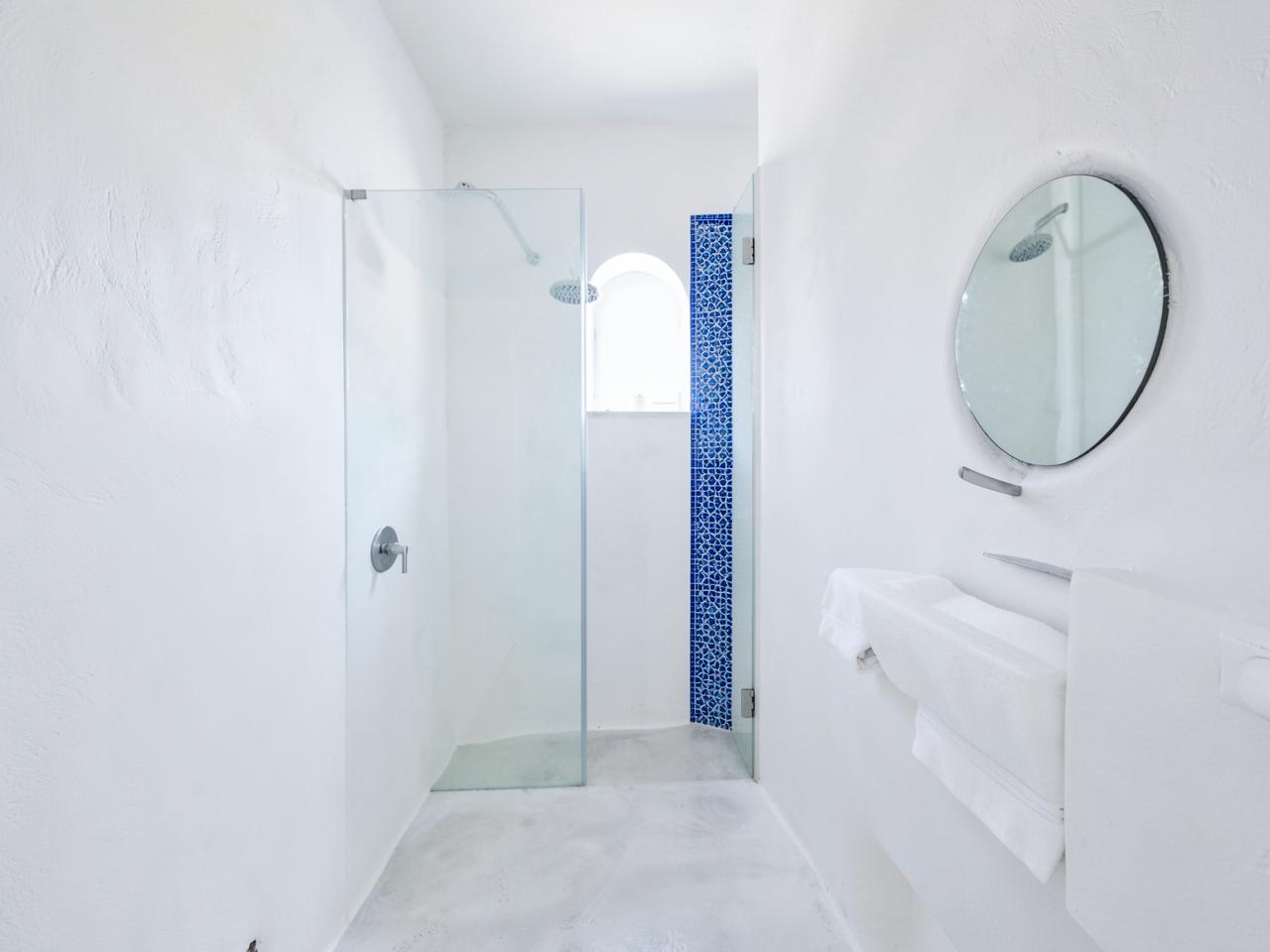 White bathroom with walk-in rain shower and blue mosaic tile detail