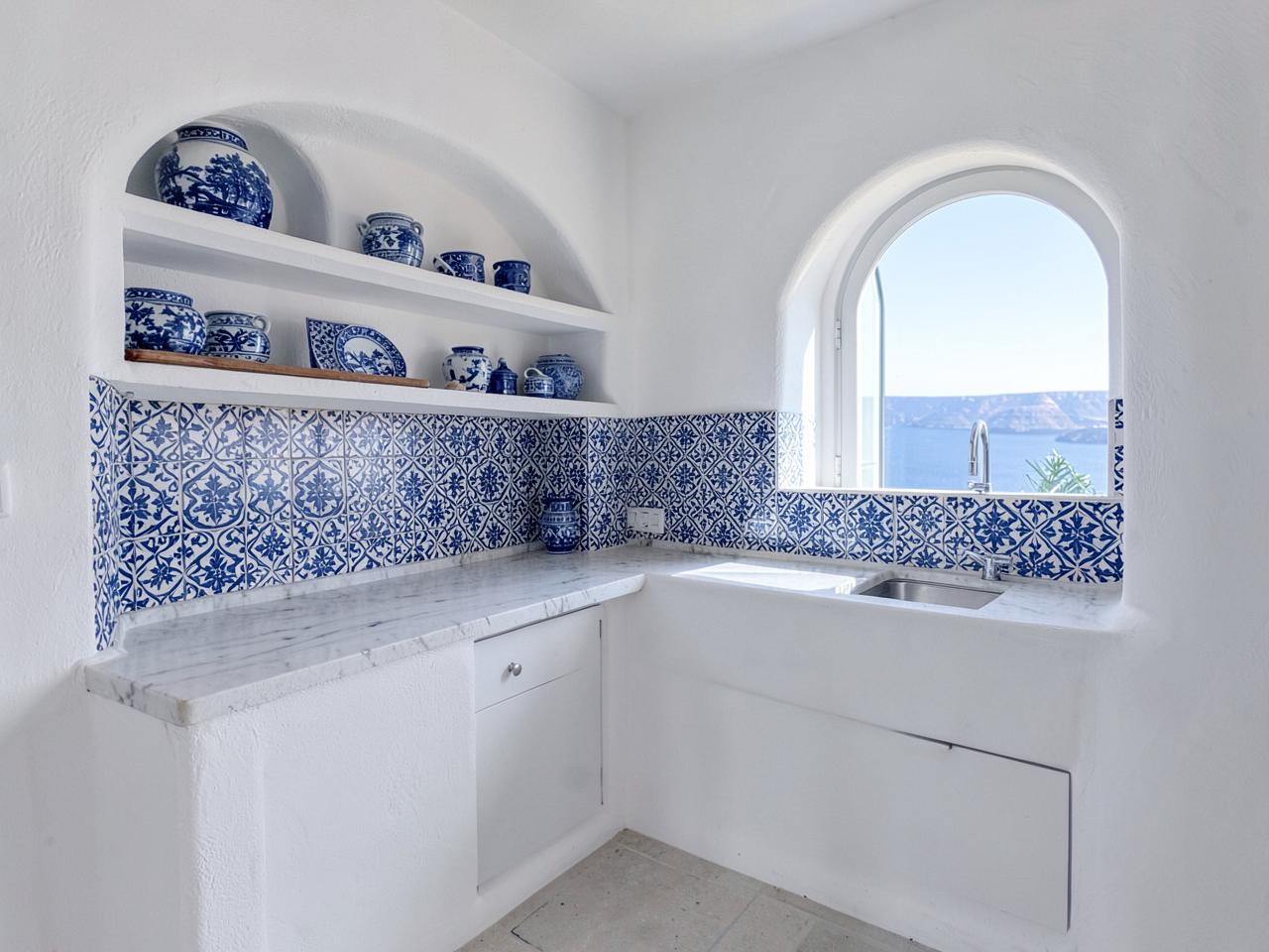 White plaster kitchen with blue and white patterned tiles and marble worktop
