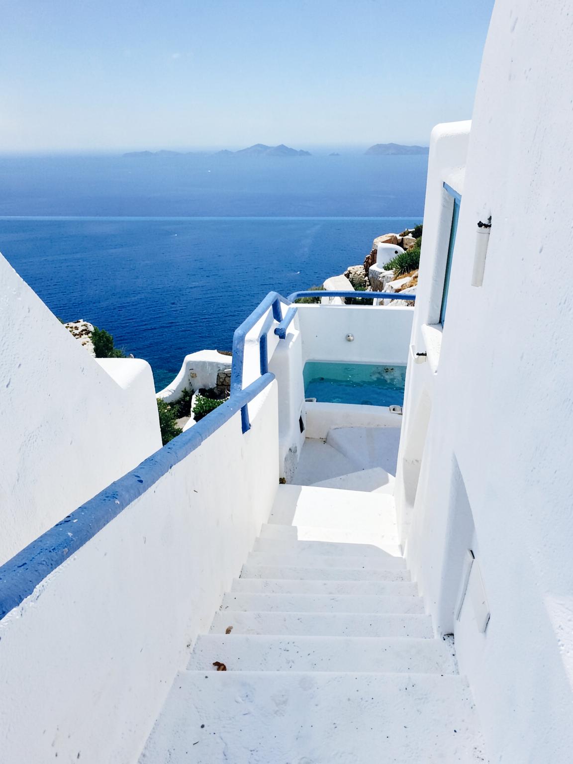 Stone stairway lined with bougainvillea leading down to a plunge pool and the sea